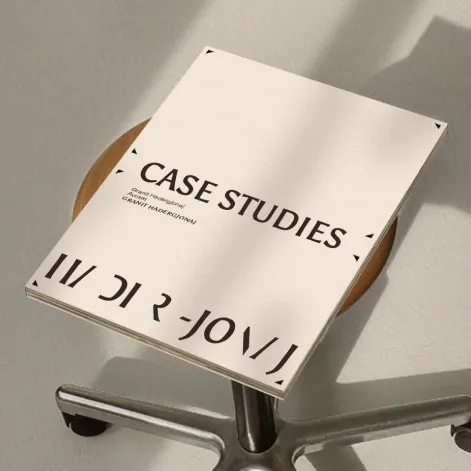 Publikacja z napisem „Case studies” leżąca na drewnianym taborecie