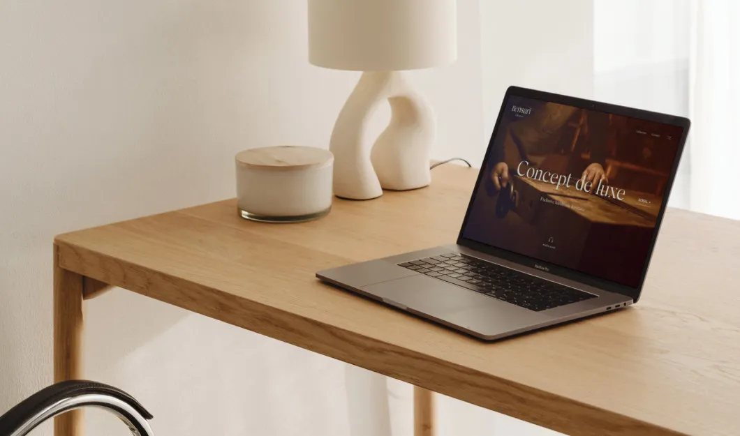 Laptop ze stroną Bensari na drewnianym biurku obok lampy i świecy