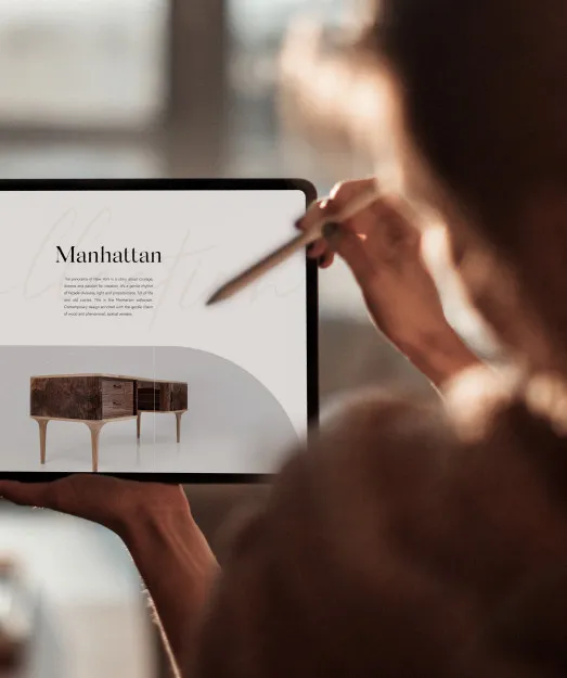 Kobieta z rysikiem przeglądająca na tablecie stronę kolekcji mebli „Manhattan”