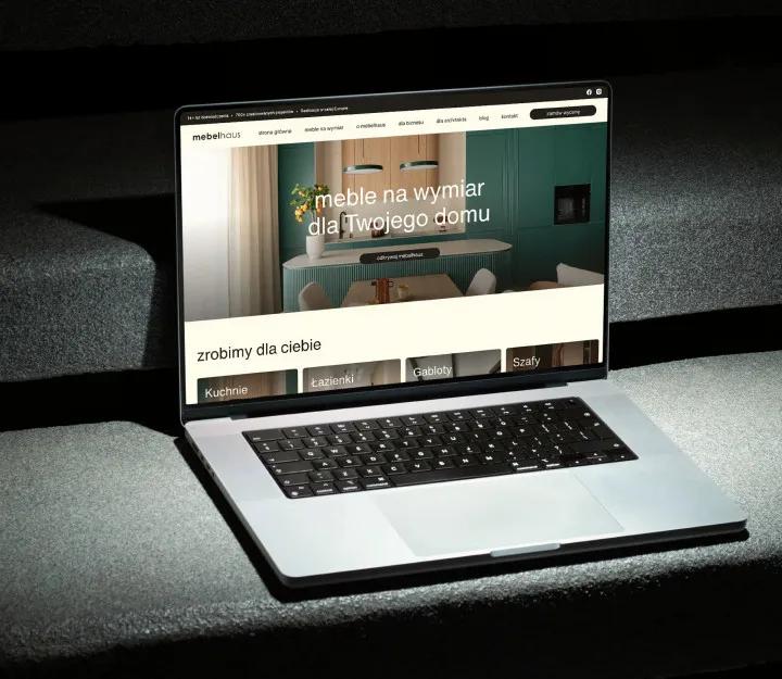 Laptop ze stroną internetową mebelhaus na ciemnych kamiennych schodach