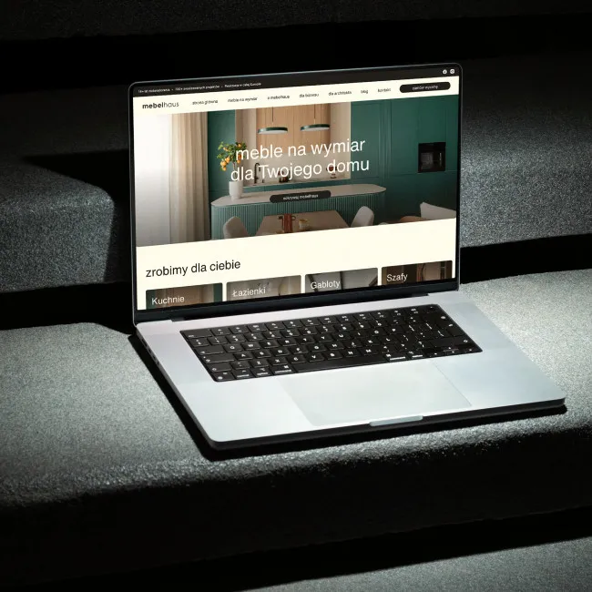 Laptop ze stroną internetową mebelhaus na ciemnych kamiennych schodach