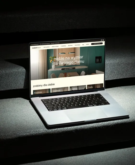 Laptop ze stroną internetową mebelhaus na ciemnych kamiennych schodach
